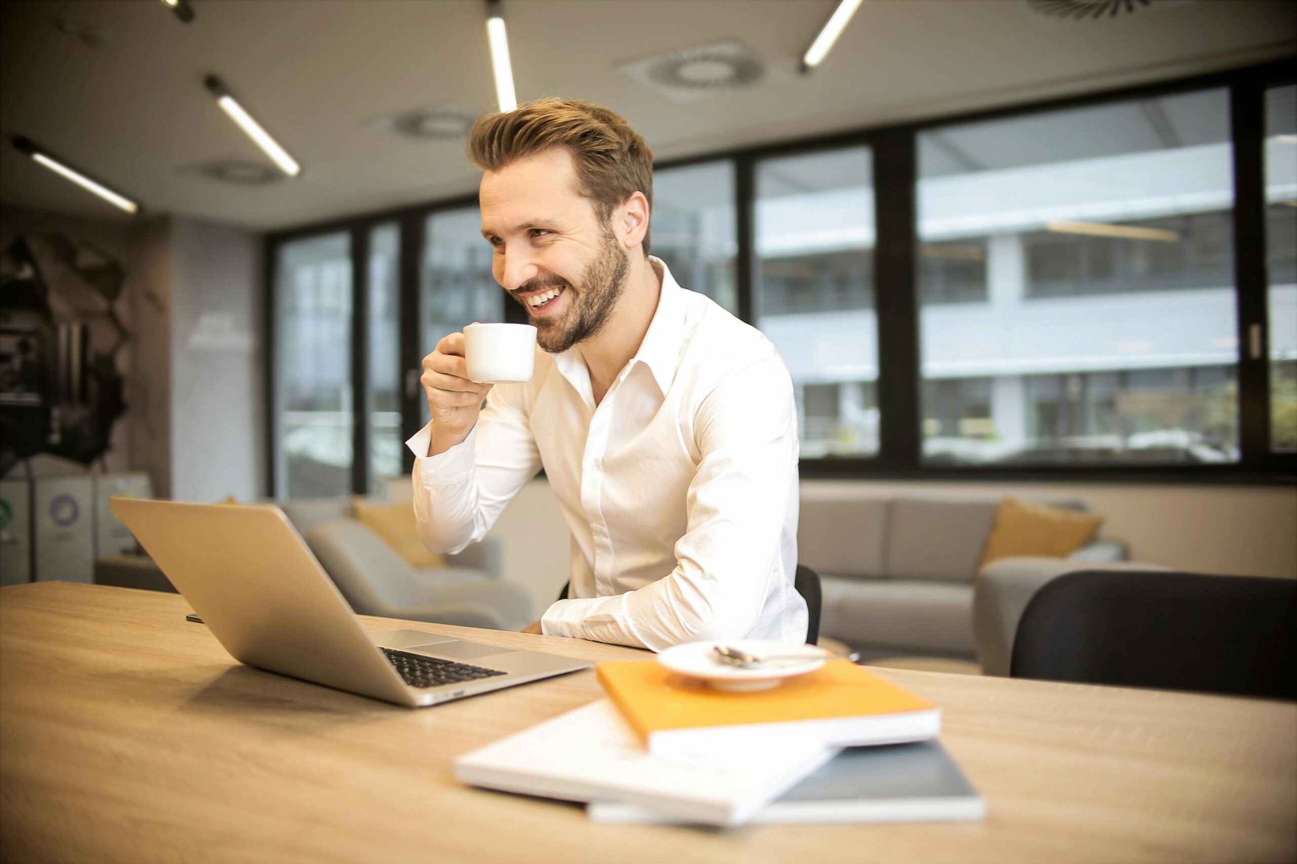 Digital Business Masterplan: Strategien für deinen Erfolg 2 Tiefenschärfe Foto Des Mannes, Der Auf Stuhl Sitzt, Während Tasse Vor Tisch Hält